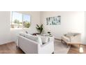 Bright living room featuring modern decor, wood floors, a comfortable sofa, and large window overlooking the yard at 1605 W Curry Dr, Chandler, AZ 85224