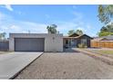 Modern exterior featuring concrete driveway, textured stucco, gray door, and well-maintained gravel landscaping at 2215 W Highland Ave, Phoenix, AZ 85015