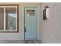 Close-up of a charming blue front door with a window, complemented by a mailbox and welcome mat at 2215 W Highland Ave, Phoenix, AZ 85015