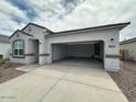 The house features a spacious driveway leading to an open two-car garage, complemented by desert landscaping at 25183 N 183Rd Dr, Wittmann, AZ 85361