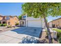 View of the two-story home, showing the long driveway, and the two-car garage, and a healthy tree in the front yard at 2847 S 161St Dr, Goodyear, AZ 85338