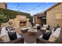 Relaxing backyard with a stone fireplace, comfortable seating, and decorative string lights at 3741 E Ember Glow Way, Phoenix, AZ 85050