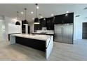 Modern kitchen with island featuring white marble countertops, sleek black cabinets, stainless steel appliances and pendant lighting at 5088 S Ponderosa Dr, Gilbert, AZ 85298