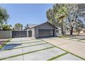 Long driveway that combines concrete and grass leading to a modern gray garage door at 5239 E Waltann Ln, Scottsdale, AZ 85254