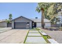 Charming single-story home featuring a modern gray garage door, desert landscaping, and a palm tree at 5239 E Waltann Ln, Scottsdale, AZ 85254