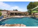 Beautiful backyard with a freeform pool, rock waterfall, tiki hut, and covered patio at 7315 W Monte Lindo Ln, Glendale, AZ 85310