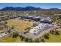 A picturesque aerial view of a school, athletic fields, and surrounding neighborhood nestled against the backdrop of scenic mountains at 8687 W Bajada Rd, Peoria, AZ 85383