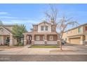 Charming two-story home featuring a covered porch with stone accents and a well-kept lawn at 12022 W Belmont W Dr, Avondale, AZ 85323