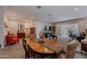 Open concept dining area features a wood table, tile floors and seamless flow to the living room at 17219 W La Luz Rd, Surprise, AZ 85387