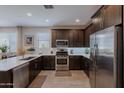 Modern kitchen boasts stainless steel appliances, dark wood cabinetry, and bright white countertops at 17219 W La Luz Rd, Surprise, AZ 85387