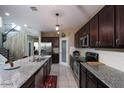 Modern kitchen features an island with granite countertop, stainless steel appliances and view to stairs at 18309 N Crestview Ln, Maricopa, AZ 85138