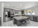 Contemporary kitchen featuring gray cabinets, stainless steel appliances, and a large island with bar seating at 22341 N 100Th Ln, Peoria, AZ 85383