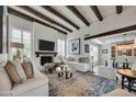 Bright living room showcasing exposed wood beams, a fireplace, and elegant, neutral-toned furniture at 3109 E Sierra Madre Way, Phoenix, AZ 85016