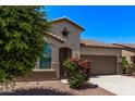 Close up of a single-story home featuring desert landscaping, arched windows, and a two-car garage at 41103 W Rio Bravo Dr, Maricopa, AZ 85138