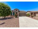 Attractive one-story home with desert landscaping, long driveway, and a two-car garage on a sunny day at 41103 W Rio Bravo Dr, Maricopa, AZ 85138