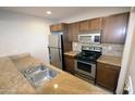 Well-lit Kitchen with stainless steel appliances, neutral stone countertops, and brown wood cabinets at 4120 N 78Th St # 116, Scottsdale, AZ 85251
