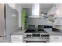 A kitchen with a stainless steel hood over an electric range and barstool seating beyond the counter at 4255 N 68Th Dr, Phoenix, AZ 85033
