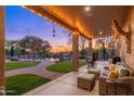 A covered patio with comfortable seating overlooks the backyard, pool, and desert landscaping at sunset at 5712 E Blue Sky Dr, Scottsdale, AZ 85266