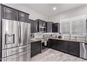 Modern kitchen featuring dark cabinetry, granite countertops, and stainless steel appliances at 11957 W Daley Ln, Sun City, AZ 85373