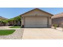 Charming single-story home featuring a beige exterior, a two car garage, and meticulous landscaping at 12425 W Willow Ave Ave, El Mirage, AZ 85335