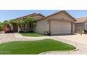 Charming single-story home featuring a beige exterior, a two car garage, and meticulous landscaping at 12425 W Willow Ave Ave, El Mirage, AZ 85335