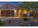 Charming single-story home with desert landscaping, a bench, and a warm welcoming entrance at night at 1654 E Jardin Pl, Casa Grande, AZ 85122