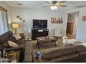 Inviting living room with plush couches, a ceiling fan, and a large TV, perfect for relaxation and entertainment at 36119 W Catalan St, Maricopa, AZ 85138