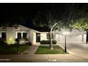 Inviting single-story home at night with landscape lighting illuminating the well-kept lawn and front entrance at 3811 E Evans Dr, Phoenix, AZ 85032