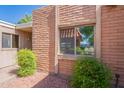 Exterior home detail showing red brick, neutral trim and a double window surrounded by leafy green bushes at 602 E Colgate Dr, Tempe, AZ 85283