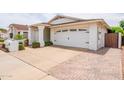 Spacious driveway leading to a white two-car garage with a charming brick paver accent at 605 W Sandra Terrace Ter, Phoenix, AZ 85023