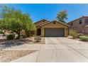 Inviting single-story home with a two-car garage, desert landscaping, and mature trees at 7003 S 23Rd Ln, Phoenix, AZ 85041