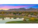 Stunning aerial view of the community with a lake and golf course against a mountain backdrop at sunset at 7424 N Via Camello Del Norte -- # 185, Scottsdale, AZ 85258