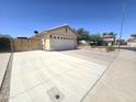Spacious driveway and garage providing ample parking and storage, featuring well-kept landscaping at 13037 W Laurel Ln, El Mirage, AZ 85335