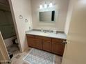 Bathroom featuring a vanity with wooden cabinets, neutral countertops, and decorative mirror at 13857 N 108Th Dr, Sun City, AZ 85351