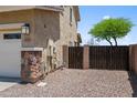 Home exterior features a two-car garage, stone accents, and a fenced gravel area at 31221 N 130Th Ln, Peoria, AZ 85383