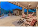 The covered patio has an outdoor kitchen and comfortable seating areas at 42101 N Olympic Fields Ct, Anthem, AZ 85086