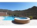 Beautiful backyard pool with an attached spa, set against a backdrop of a natural desert landscape at 42101 N Olympic Fields Ct, Anthem, AZ 85086