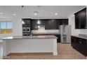 Spacious kitchen featuring an island, stainless steel appliances, and ample dark wood cabinets with modern lighting at 4853 N 183Rd Ln, Goodyear, AZ 85395