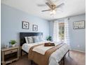 Serene bedroom boasts soft blue walls, a ceiling fan, and a window overlooking a peaceful outdoor view at 811 E Eugie Ave, Phoenix, AZ 85022