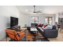 Bright living room with an orange accent chair and a large grey sectional sofa and ceiling fan at 13918 N 78Th Ave, Peoria, AZ 85381
