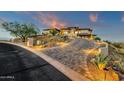 Curving paver driveway leading to a hillside home with mature landscaping and exterior lighting for enhanced curb appeal at 16119 N Desert Fox Pkwy, Fountain Hills, AZ 85268