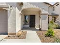 Inviting front entrance with an arched entryway, dark security door, and manicured desert landscaping at 19664 W Woodlands Ave, Buckeye, AZ 85326