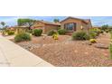 View of the front yard, showcasing the desert landscaping with rocks, cacti, and various desert plants at 19722 N Regents Park Dr, Surprise, AZ 85387
