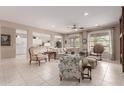 Spacious living room with tile flooring, large windows, a ceiling fan, and an open view of the kitchen at 19722 N Regents Park Dr, Surprise, AZ 85387