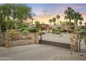 Elegant property featuring a brick driveway and gate entrance, surrounded by beautiful mature landscaping at 4836 E Moonlight Way, Paradise Valley, AZ 85253