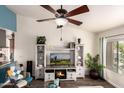 Bright living room with wood floors, entertainment center with fireplace, and modern ceiling fan at 6160 S Pebble Beach Dr, Chandler, AZ 85249