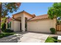 Beautiful home featuring a two-car garage, tiled roof, arched entry, and verdant landscaping at 9575 S Ash Ave, Tempe, AZ 85284
