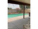 A covered outdoor patio overlooks the backyard pool with string lights and a privacy fence at 11640 N 74Th Dr, Peoria, AZ 85345