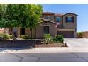 Exterior view of a two-story home with a three-car garage, stone accents, and green landscaping at 19427 W Colter St, Litchfield Park, AZ 85340