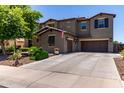 Two-story stucco home featuring a three-car garage, mature landscaping, and a tiled roof at 19427 W Colter St, Litchfield Park, AZ 85340
